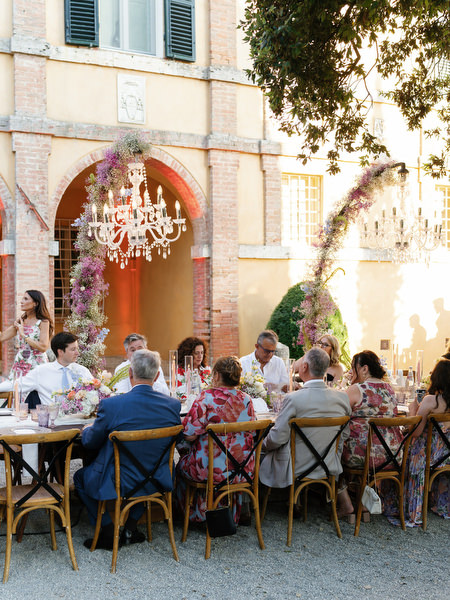 Guests dining beneath floral arches and chandeliers at La Foce wedding reception