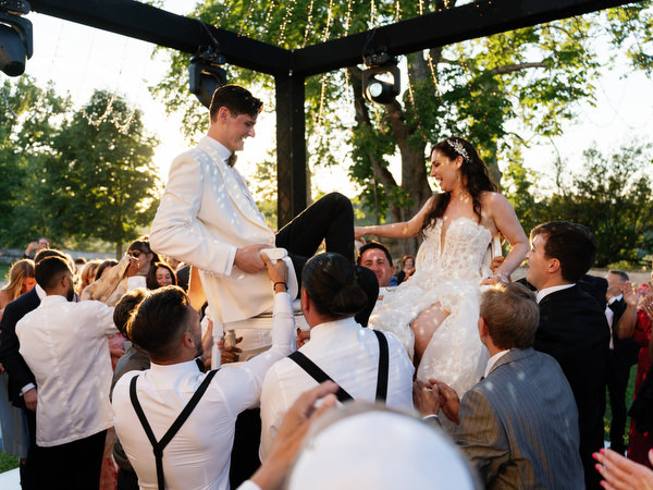 Bride and groom lifted on chair during Jewish hora at Villa Corsini Tuscany, Florence destination wedding.