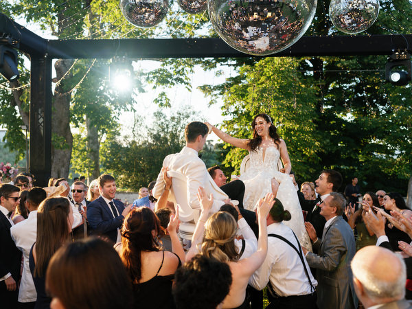 Bride and groom lifted on chairs during Jewish wedding hora at Villa Corsini Tuscany.