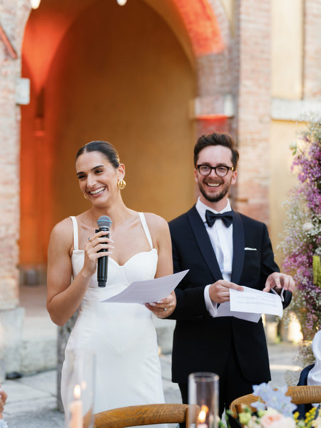 Bride giving heartfelt speech during candlelit luxury wedding reception in Tuscany