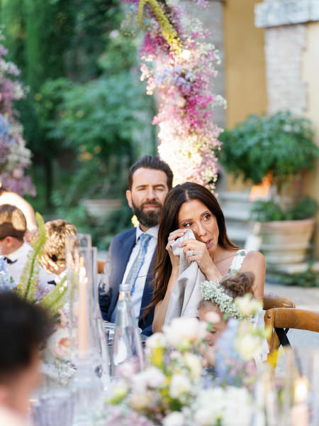 Emotional guest wiping away tears during intimate wedding dinner in Tuscany