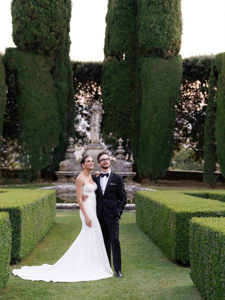 Bride and groom posing in manicured Renaissance gardens at La Foce estate in Tuscany