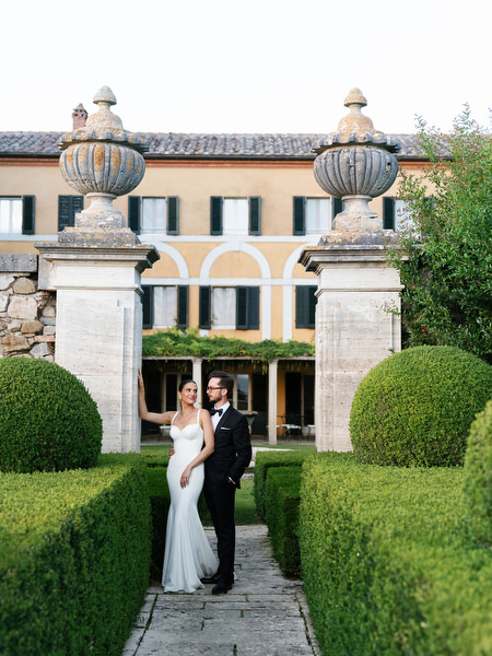 Newlyweds framed by historic stone pillars at La Foce wedding venue in Tuscany