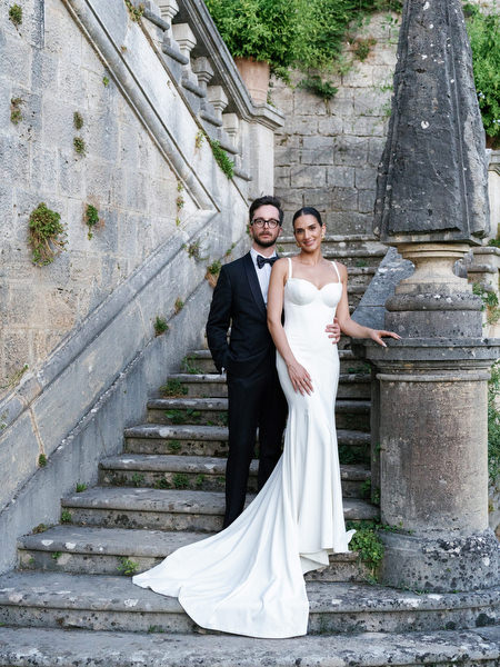 Bride and groom posing on historic stone staircase at La Foce in Tuscany