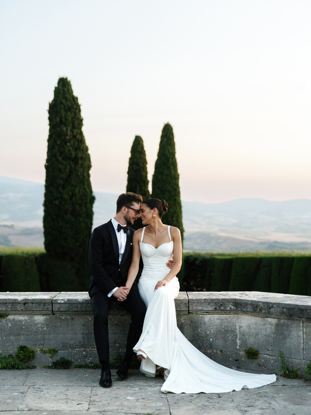 Bride and groom seated on terrace overlooking rolling hills of the Tuscan countryside