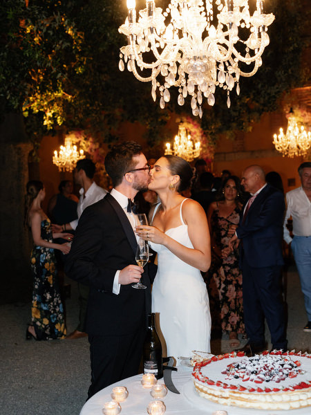 Bride and groom toasting beside wedding cake during luxury Tuscany reception