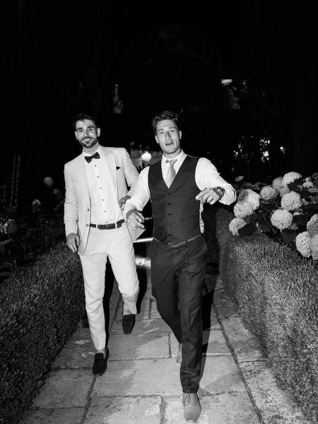 Black and white candid of guests walking through illuminated garden at night