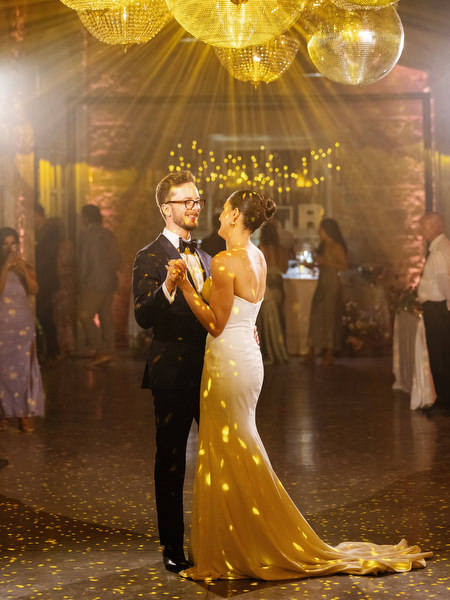 Bride and groom sharing their first dance beneath sparkling disco lights at luxury Tuscany wedding