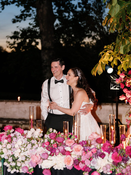 Bride laughing beside floral reception table at Villa Corsini a Mezzomonte Tuscany.