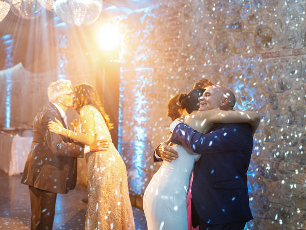 Bride and father embracing on dance floor beneath sparkling lights at Tuscany destination wedding
