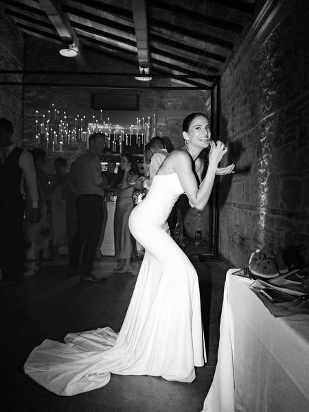 Bride playfully leaning toward dessert table during high-energy Tuscany wedding after-party