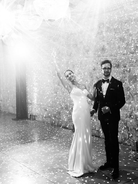 Black and white portrait of newlyweds celebrating under confetti during luxury estate wedding