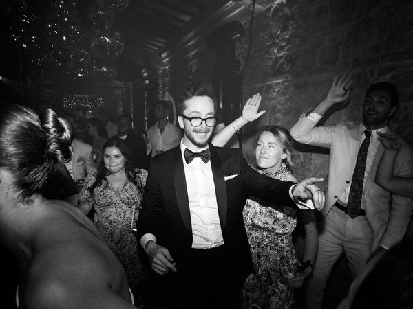 Groom dancing surrounded by cheering guests during destination wedding reception in Tuscany