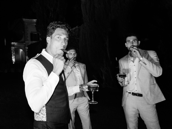 Groomsmen smoking and drinking during late-night wedding party in Tuscany