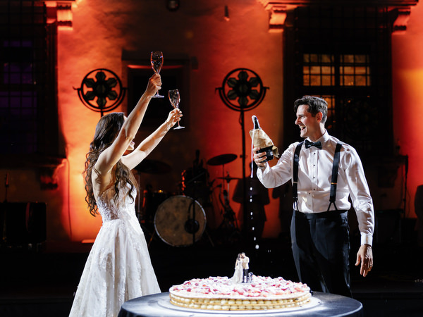 Bride and groom raising glasses during cake celebration at Villa Corsini Florence.