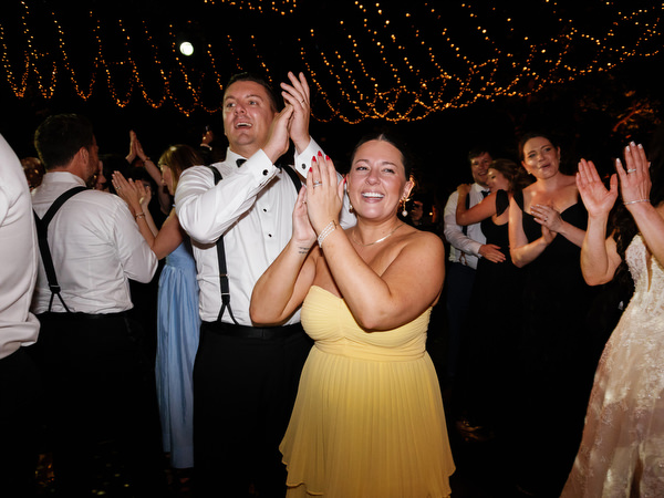 Wedding guests clapping on dance floor beneath string lights at Tuscany villa reception in Florence.
