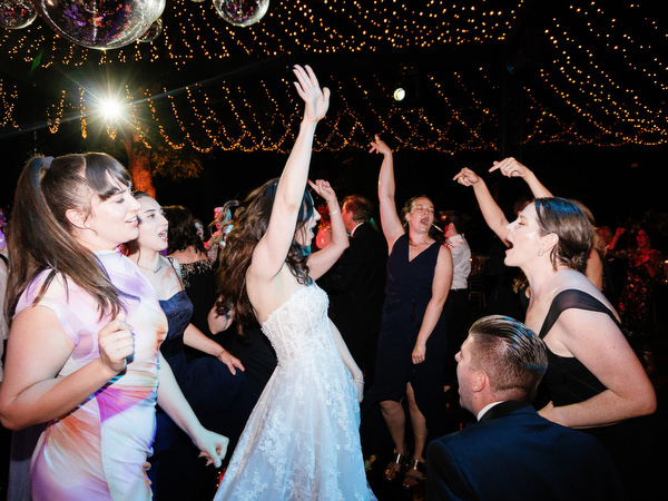 Bridesmaids dancing beneath twinkle lights at Villa Corsini Tuscany wedding party.