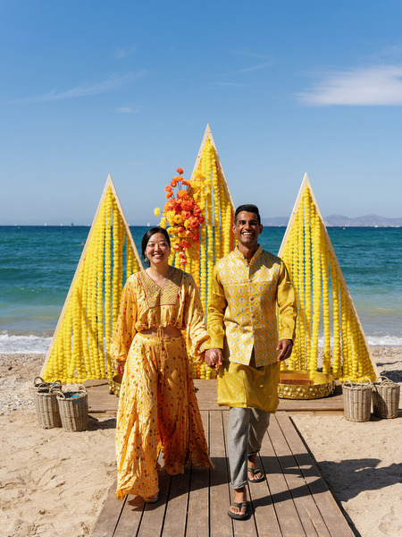 Couple walking along beach during Haldi celebration
