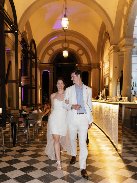 Bride and groom holding hands under historic Florence arches