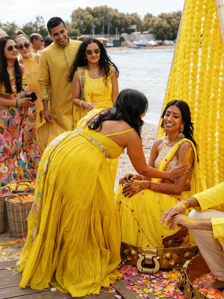 Bride sitting while turmeric is applied during Haldi