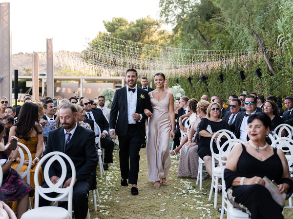 Couple walking down the aisle smiling at Island Resort Athens Riviera.