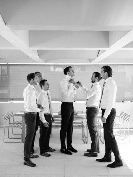Groom sharing a candid moment with groomsmen at Island Resort, stylish Athens wedding venue on the Athenian Riviera.