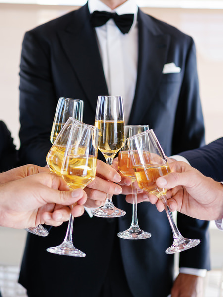 Champagne toast during groom prep at Island Resort, elegant black-tie wedding in Athens on the Athenian Riviera.