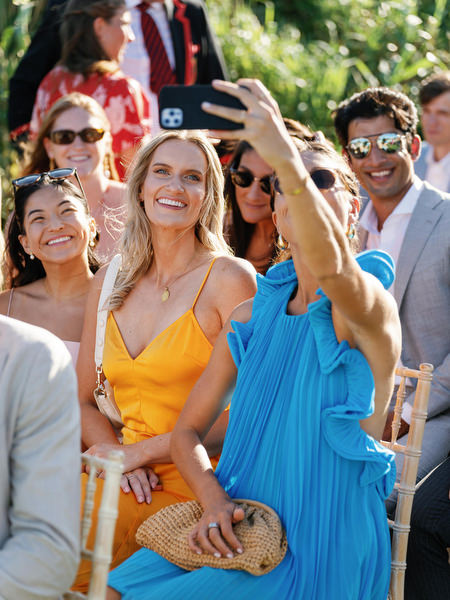 Guests taking selfies before the ceremony at Island Resort, vibrant Athens Riviera wedding atmosphere.