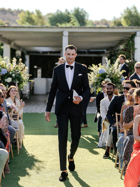 Groom walking down the aisle at Island Resort, black-tie Athens Riviera wedding ceremony in Greece.