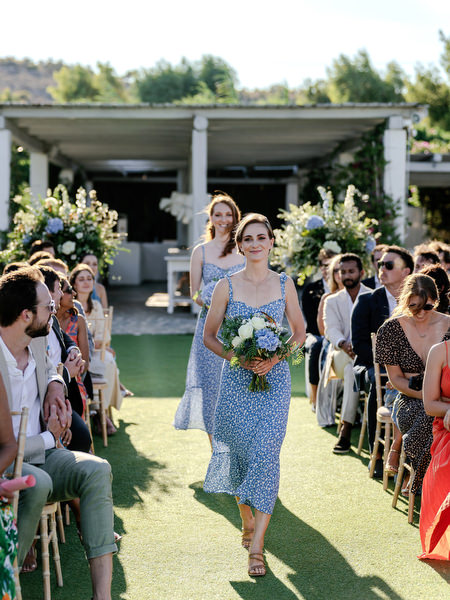 Bridesmaid walking down the aisle at Island Resort, elegant Athens Riviera wedding ceremony in Greece.