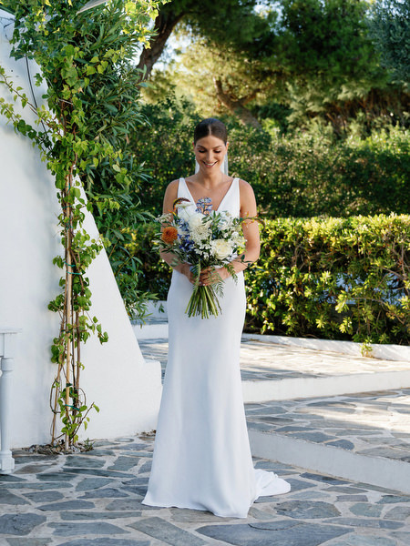 Bride holding bouquet beneath Mediterranean archways at Island Resort, Athens Riviera wedding venue.