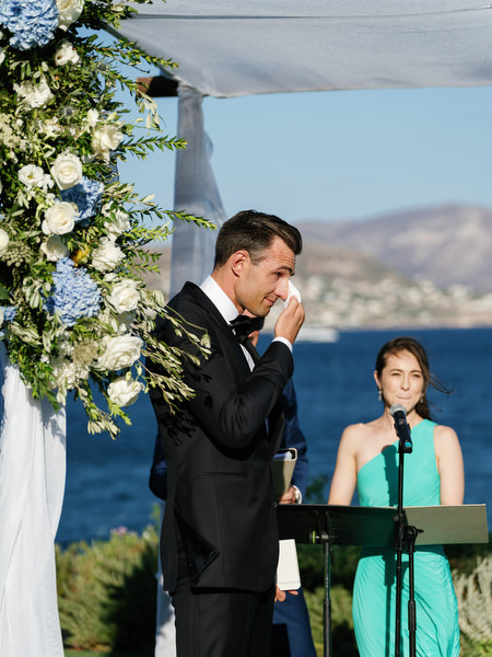 Groom during ceremony at Island Resort with Aegean Sea backdrop, luxury Athens destination wedding in Greece.