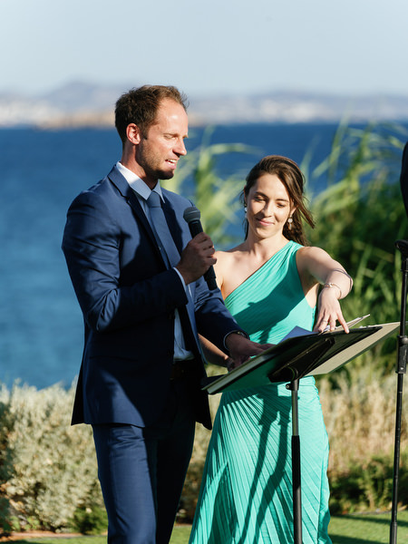 Wedding officiant speaking during seaside ceremony at Island Resort, Athens Riviera destination wedding in Greece.