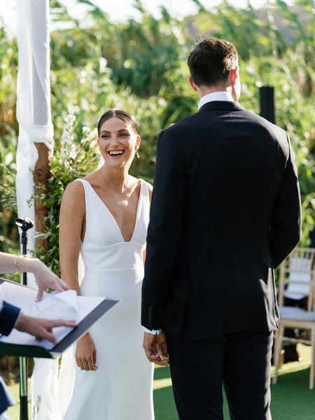 Bride laughing during vows at Island Resort, romantic Athens Riviera wedding ceremony.