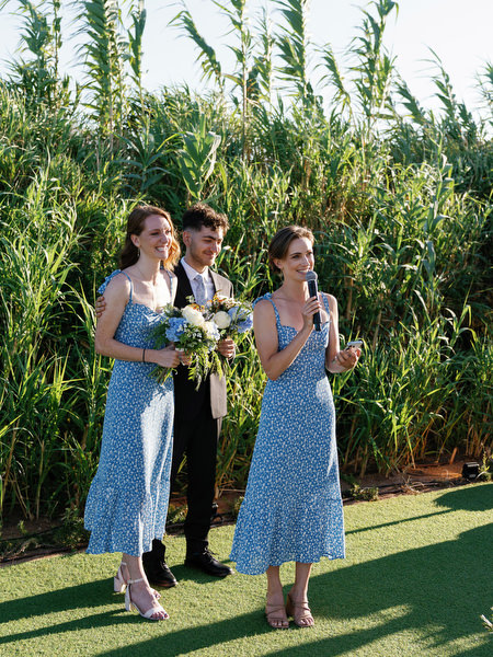Bridesmaids delivering ceremony reading at Island Resort, Athens Riviera seaside wedding.
