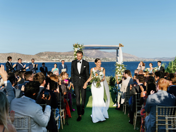 Bride and groom walking down the aisle at Island Resort, seaside Athens Riviera wedding celebration.