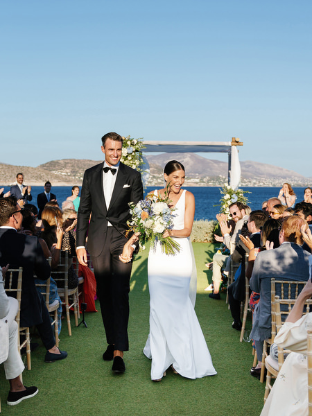 Newlyweds celebrating as they walk down the aisle at Island Resort, luxury Athens Riviera wedding.