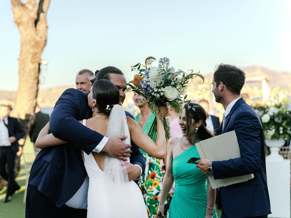Bride hugging guest following seaside ceremony at Island Resort, luxury Athens wedding celebration.