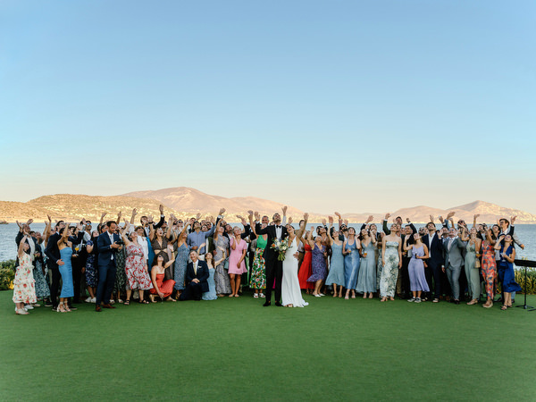 Full wedding guest group photo at Island Resort, sunset Athens Riviera destination wedding.