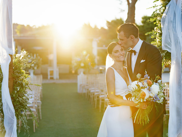 Bride and groom kissing at sunset at Island Resort, elegant Athens Riviera seaside wedding in Greece.