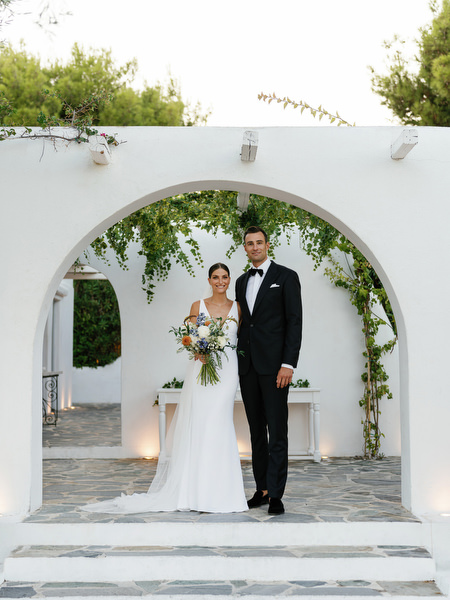 Bride and groom posing beneath iconic arch at Island Resort, luxury Athens Riviera wedding venue.
