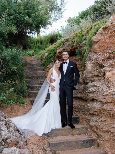 Bride and groom on stone steps near the sea at Island Resort, elegant Athens Riviera wedding photography.