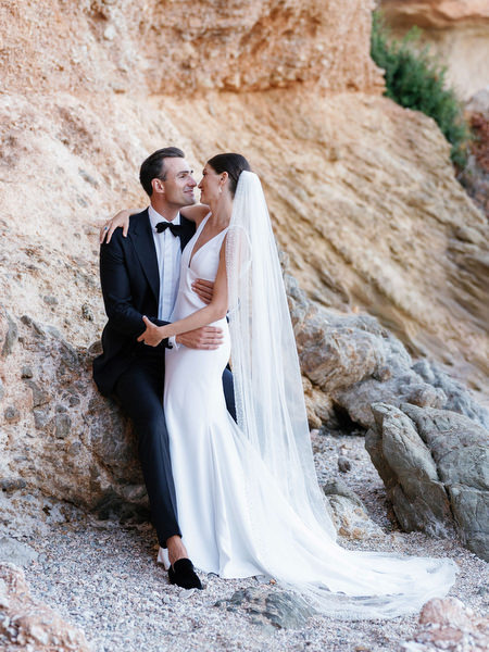 Bride and groom seated by the sea at Island Resort, romantic Athens Riviera wedding in Greece.