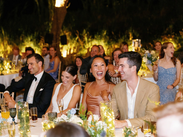 Wedding guests laughing during night reception at Island Resort, lively Athens Riviera wedding celebration.