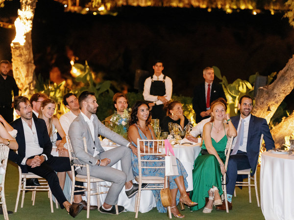 Wedding guests listening to reception speech at Island Resort, romantic Athens Riviera wedding night.