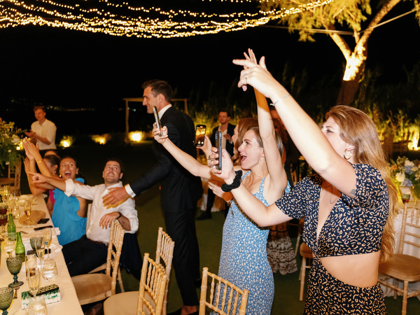 Guests cheering during Island Resort wedding party, lively Athens Riviera night celebration.