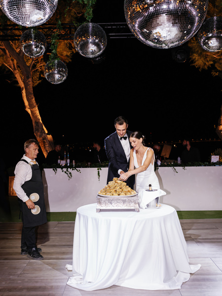 Bride and groom cutting wedding cake at Island Resort, Athens Riviera luxury wedding reception.