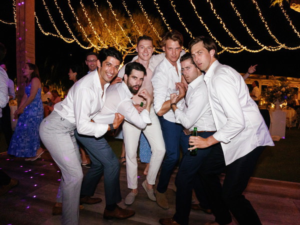 Groomsmen celebrating on dance floor at Island Resort, energetic Athens Riviera wedding party.