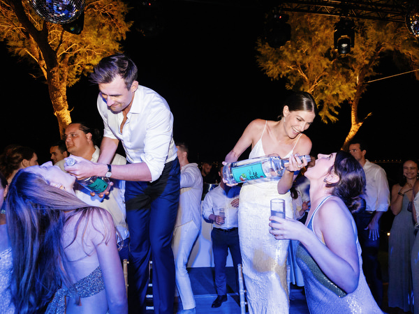 Bride pouring a celebratory drink on the dance floor at Island Resort, lively Athens Riviera Jewish wedding reception.