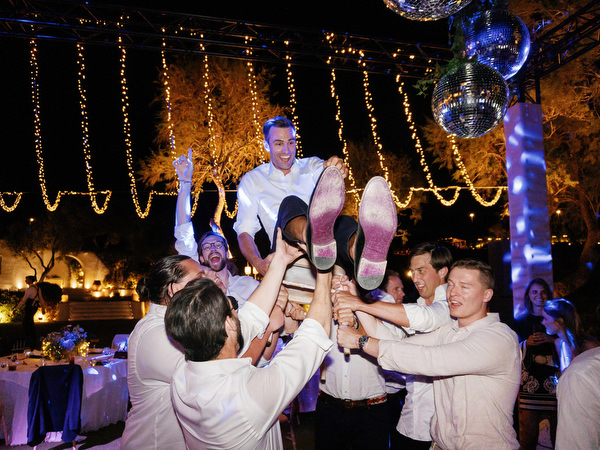 Groom lifted in the air during hora at Island Resort, luxury Athens Riviera Jewish wedding.